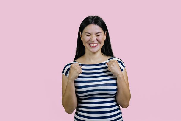 Portrait of enthusiastic asian woman rejoicing success. Celebrating victory over pink. - Foto, Bild