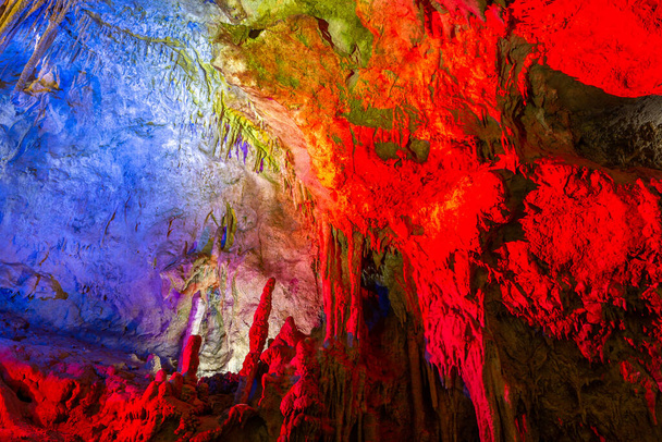 Prometheus Cave Natural Monument, Kutaisi, Georgia, with hanging stone curtains, stalactites and stalagmites, colorful illuminated rock formations. - Фото, изображение