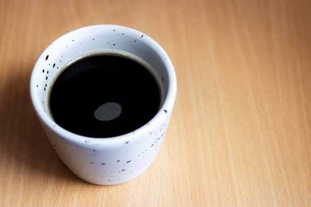 木のテーブルに置かれた白い日本風のカップに淹れたばかりのコーヒー. - 写真・画像