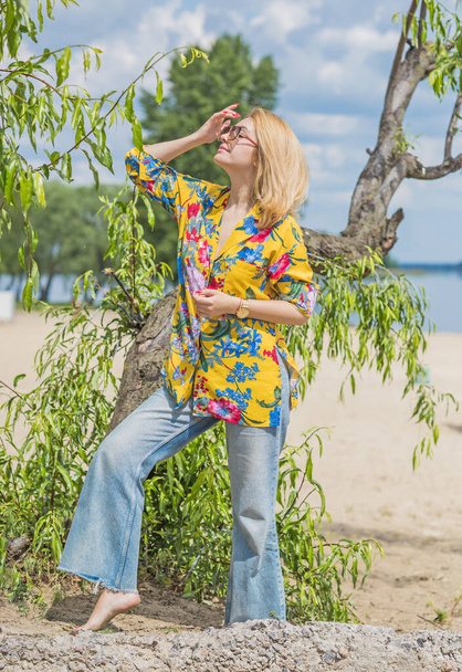 Женщина в красочной хлопчатобумажной модной рубашке и раздутых джинсах. Модная одежда, концепция отпуска. Стиль 70-х - Фото, изображение