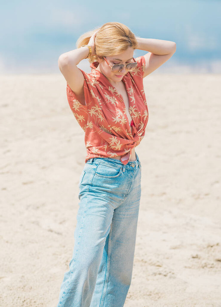 Kobieta w kolorowe bawełniane modne koszulki i rozpalone dżinsy. Modne ubrania, pomysł na wakacje. Styl lat 70. - Zdjęcie, obraz