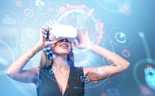 Smiling businesswoman in vr glasses look up, double exposure, earth sphere with diverse digital icons hologram, glowing hud chain. Concept of virtual world - Photo, image