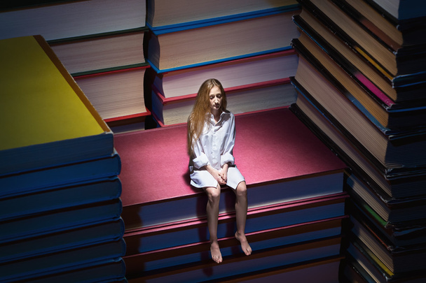 Small young woman sitting on books - Photo, image
