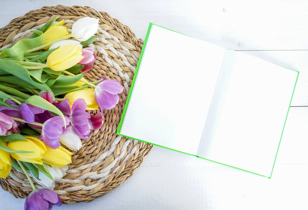 tulipas amarelas, roxas e brancas com um livro sobre terra de madeira branca com espaço para texto - Foto, Imagem