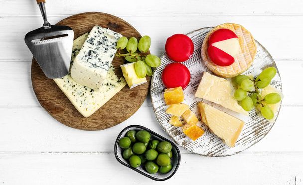 Different kinds of cheese served with green olives, tomato and grape for gourmet nutrition. Organic parmesan and brie delicatessen - Zdjęcie, obraz