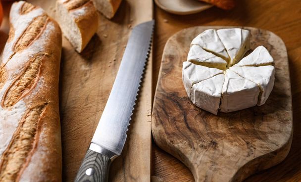 Delicious brie cheese with white mold cutting for a breakfast on a kitchen table - 写真・画像