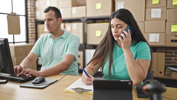 Два сотрудника, работающие за телефоном в офисе электронной коммерции - Кадры, видео