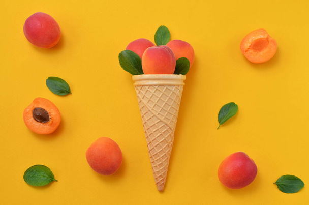 colorful food background ripe apricots with leaves on yellow background - Foto, afbeelding