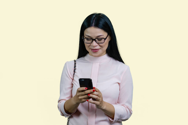 Joven mujer de negocios asiática está enviando mensajes de texto algo en smartphone. Aislado sobre fondo blanco. - Foto, imagen