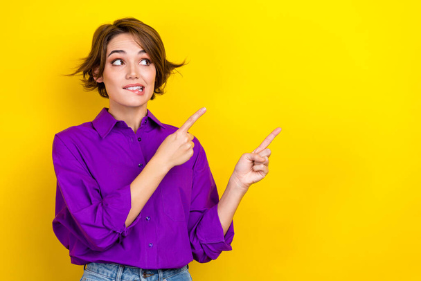 Photo of worker lady direct fingers empty space bite lips mischief face wear office clothes isolated yellow color background. - Zdjęcie, obraz