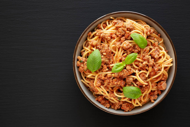 Domácí rajčatový bazalkový salám špagety v misce na černém pozadí, horní pohled. Plocha ležela shora, shora.  - Fotografie, Obrázek