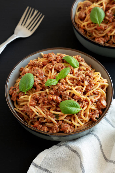 Domácí rajčatová bazalka klobása špagety v misce na černém pozadí, boční pohled. - Fotografie, Obrázek