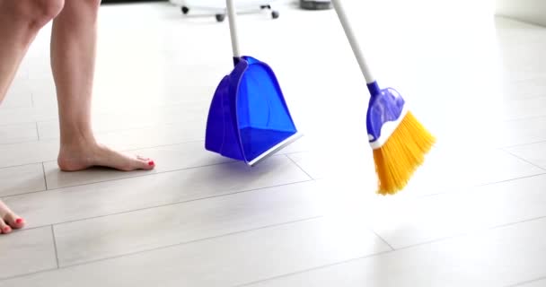Nainen lakaistaan lattia luuta ja rikkalapio lähikuva 4k elokuva hidastettuna. Asuntojen siivous ja kotityöt käsite  - Materiaali, video