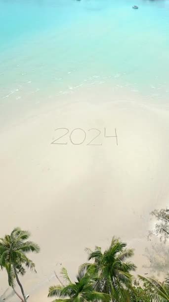 Úžasný letecký pohled na rok 2024 napsaný na bílém písku na tropické pláži v Thajsku, s kokosovými palmami a křišťálově čistou tyrkysovou vodou. - Záběry, video