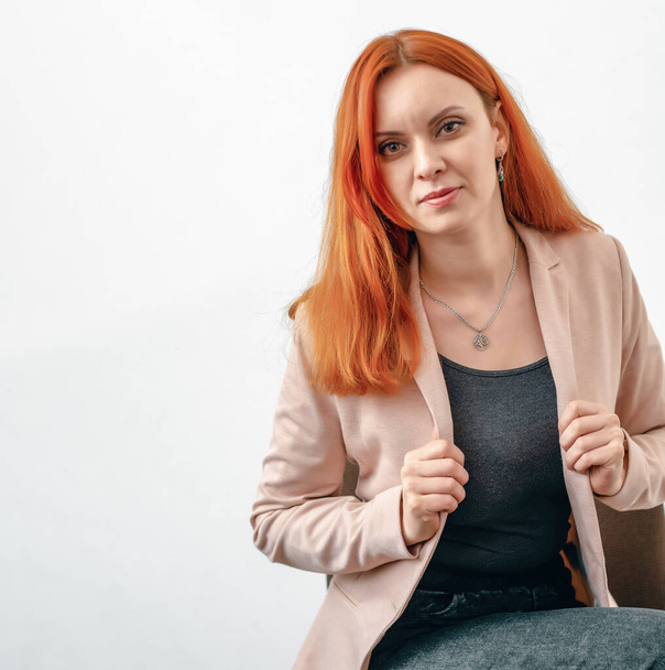 Portrait of a red-haired woman in a light jacket on white background - 写真・画像