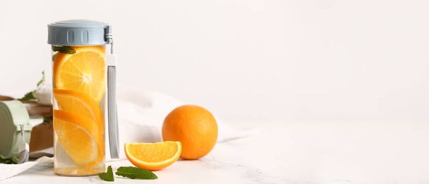 Pullo oranssia infusoitua vettä valoisalla pohjalla ja tilaa tekstille - Valokuva, kuva