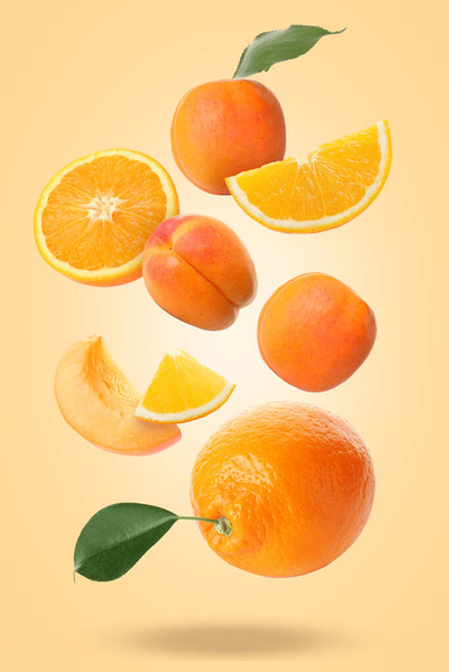 Flying apricots and oranges on beige background - Φωτογραφία, εικόνα