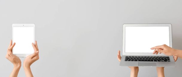 Banner mit Frauenhänden, modernem Laptop und Tablet-Computer auf grauem Hintergrund - Foto, Bild