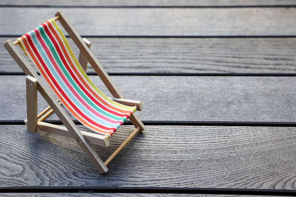 Toy sun lounger on grey wooden background - Foto, imagen