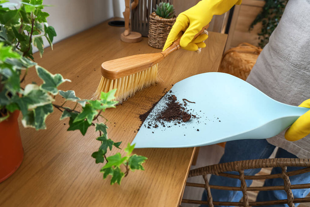 Домохозяйка убирает стол с щеткой и совок дома, крупным планом - Фото, изображение