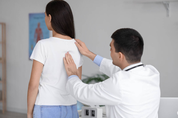 Male doctor checking posture of young woman in clinic - Foto, Imagem