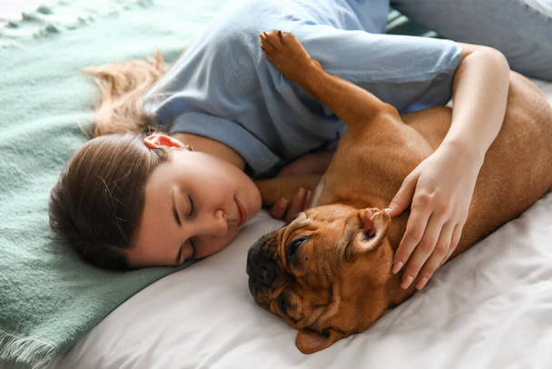 Junge Frau mit süßer französischer Bulldogge im Schlafzimmer liegend, Nahaufnahme - Foto, Bild