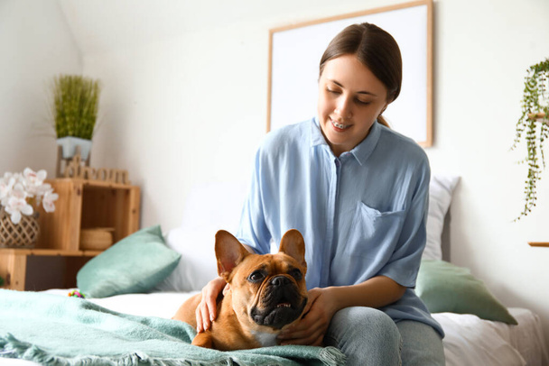 Young woman with cute French bulldog in bedroom - Photo, image