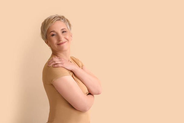 Mature blonde woman on beige background - Zdjęcie, obraz