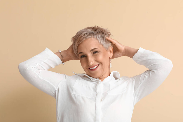 Mature blonde woman on beige background - Valokuva, kuva