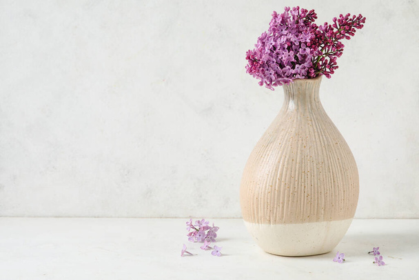 Vase with aromatic lilac flowers on light background - 写真・画像