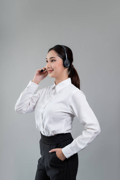 Atrakcyjny azjatycki operator call center kobieta ze szczęśliwym uśmiechem twarzy reklamuje możliwość pracy na pustej przestrzeni, noszenie formalnego garnituru i słuchawki na konfigurowalnym tle izolowane. Entuzjastycznie - Zdjęcie, obraz