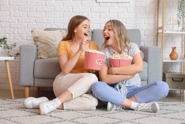 Giovani sorelle che mangiano popcorn a casa - Foto, immagini