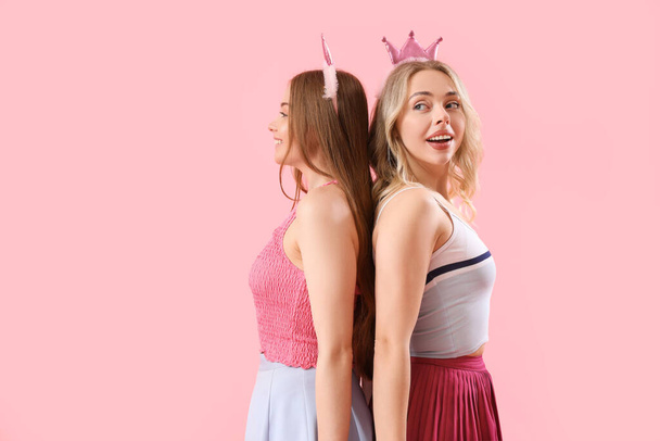 Young sisters in crowns on pink background - Photo, Image