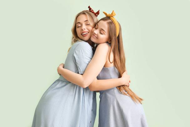 Молодые сестры обнимаются на зеленом фоне - Фото, изображение