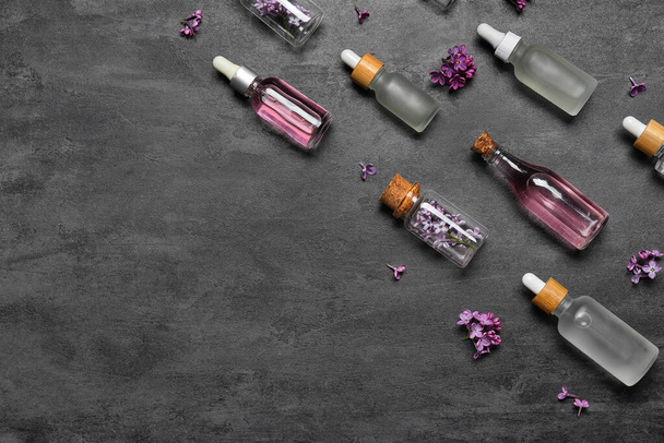 Composición con botellas de aceite esencial de lila y flores sobre fondo oscuro - Foto, imagen