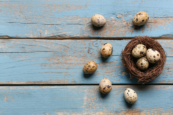 Φωλιά με φρέσκα αυγά ορτυκιού σε μπλε ξύλινο φόντο - Φωτογραφία, εικόνα