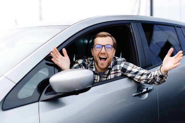 Klient człowiek siedzi w salonie samochodowym i uśmiechnięty, wybierając auto i chcąc kupić nowy samochód w salonie dealerskim. Koncepcja sprzedaży samochodów - Zdjęcie, obraz