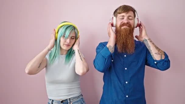 Mies ja nainen pari kuuntelee musiikkia tanssia yli eristetty vaaleanpunainen tausta - Materiaali, video