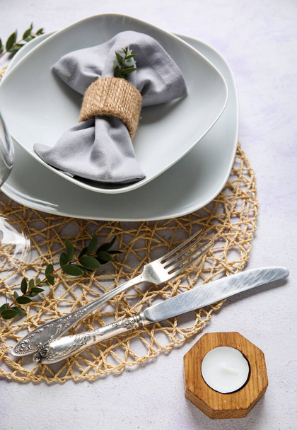 Wicker mat with stylish table setting and candle on grunge white background - Photo, image