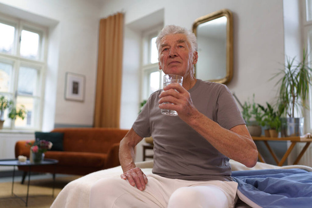Portrét staršího muže, jak pije vodu po prášcích. Význam hydratace pro starší osoby. - Fotografie, Obrázek
