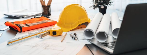 Architectural designed building blueprint layout and engineer tool for designing blueprint with contractor project document on engineer workspace table in office with safety helmet or hardhat. Insight - Φωτογραφία, εικόνα
