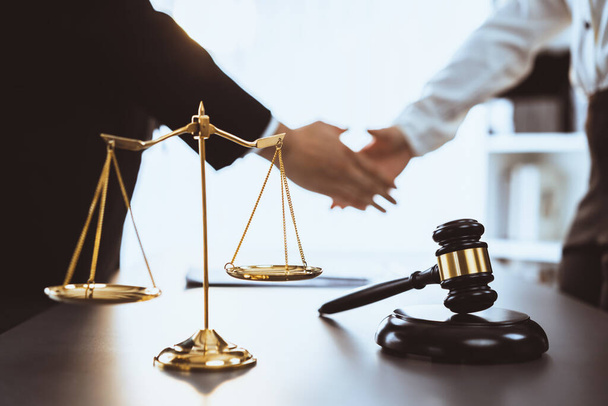Focus gavel and justice scale on blur background of lawyer colleagues handshake after successful legal deal for lawsuit to advocate resolves dispute in court ensuring trustworthy partner. Equilibrium - Foto, Imagen