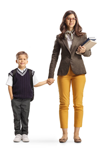 Full length portrait of a young female teacher holding hand with a student isolated on white background - Фото, изображение