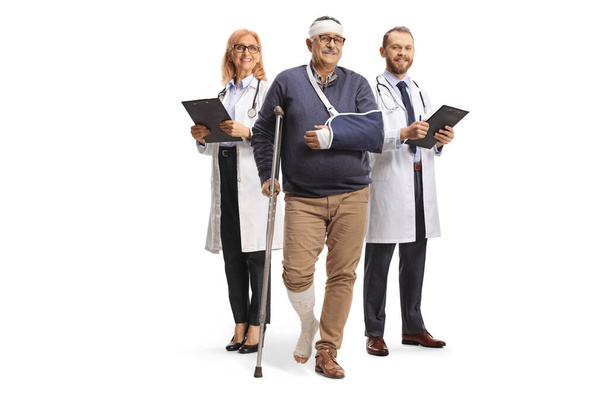 Mature male patient with leg and head injury standing in front of two doctors isolated on white background - Foto, immagini