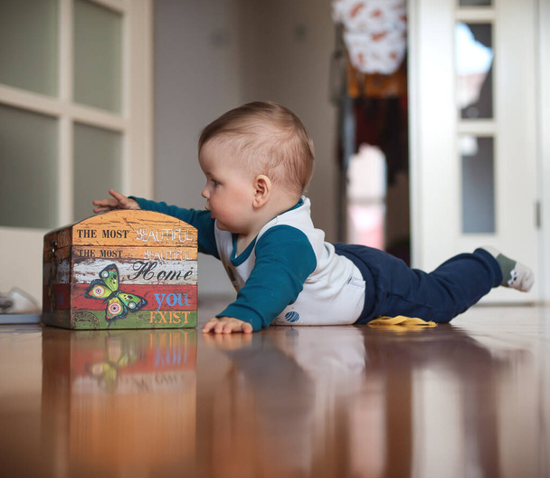 Cute baby boy crawls on the home floor, explore the world and things around him. Love and family emotion - 写真・画像