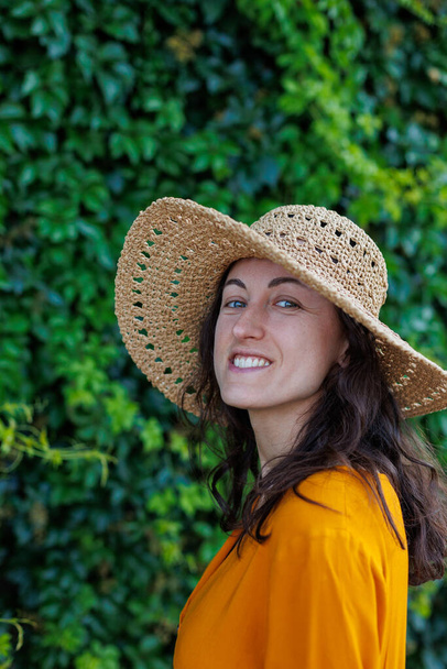 portrait of a young happy brunette in a straw hat. The girl smiles and enjoys her vacation outdoors.Close-up. - 写真・画像