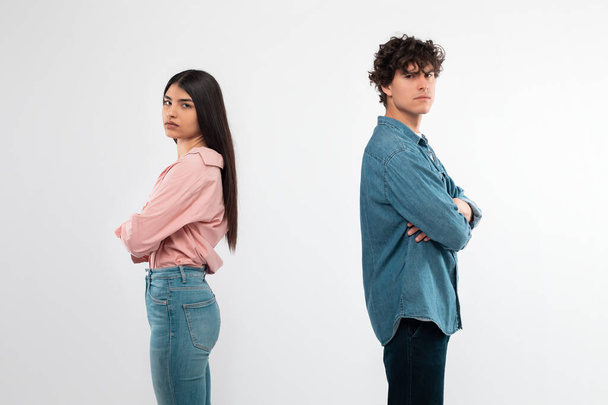 Breakup. Offended Couple After Conflict Standing Back To Back Looking At Camera Over White Background In Studio. Shot Of Unhappy Young Girlfriend And Boyfriend Having Disagreement. Bad Relationship - Photo, Image