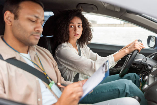 Anxious Learner Driver Woman Selhání řidičský průkaz test, Při pohledu na instruktora Muž po sezení v autě, Jako učitel psaní poznámek o její dovednosti řízení vozidla. Pohled z boku, Selektivní zaměření - Fotografie, Obrázek
