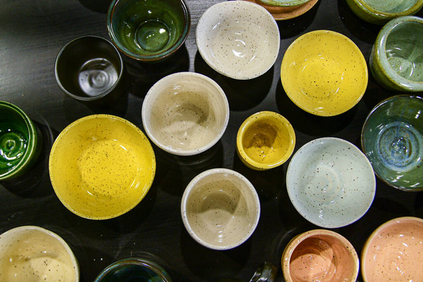 Top view flay lay composition of table full of different colours shapes and sizes handmade speckled pottery ceramics cups bowls - Foto, afbeelding