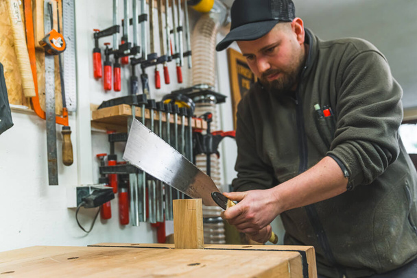 Carpinteiro usando serra japonesa para cortar madeira na loja trabalhador focado homem no trabalho. Foto de alta qualidade - Foto, Imagem